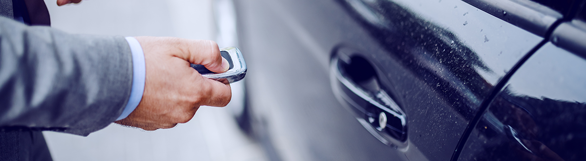 Close up of a person locking their vehicle with a key fob