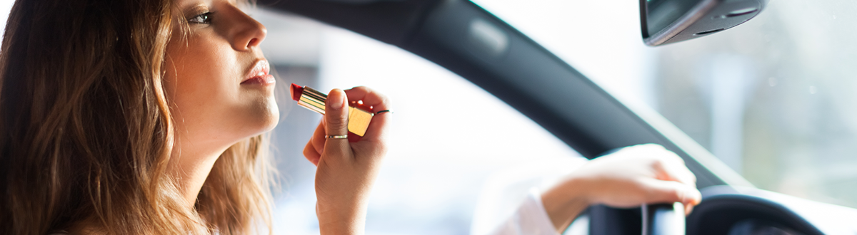 Woman applying lipstick while driving