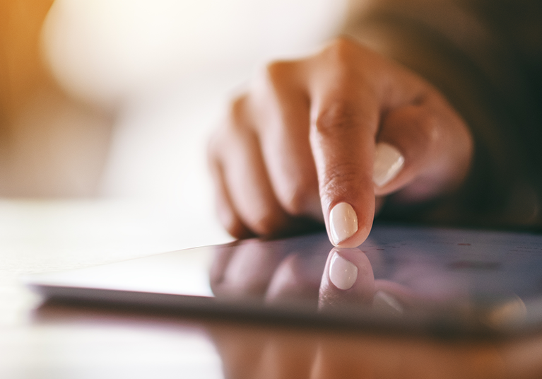 member-info_go-paperless-for-ease_blog_hero-mobile_767x536 Closeup of a person with white painted nails pointing at a tablet PC on a wooden table.