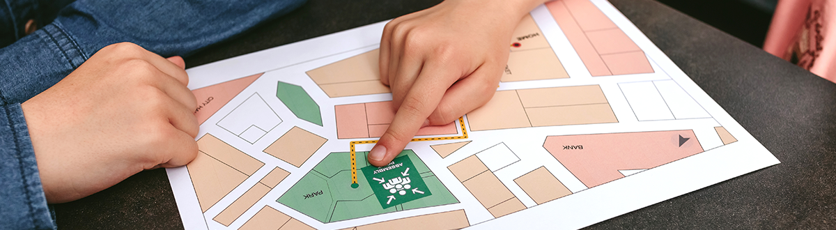 Close up of two hands pointing to a home’s location on a wildfire evacuation map
